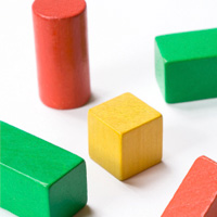 Quader, Würfel und Zylinder (Holzbauklötze) in den Farben rot, grün und gelb sind zu erkennen.